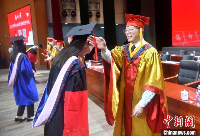 图为校领导为毕业生代表执拨穗礼。　吕明 摄