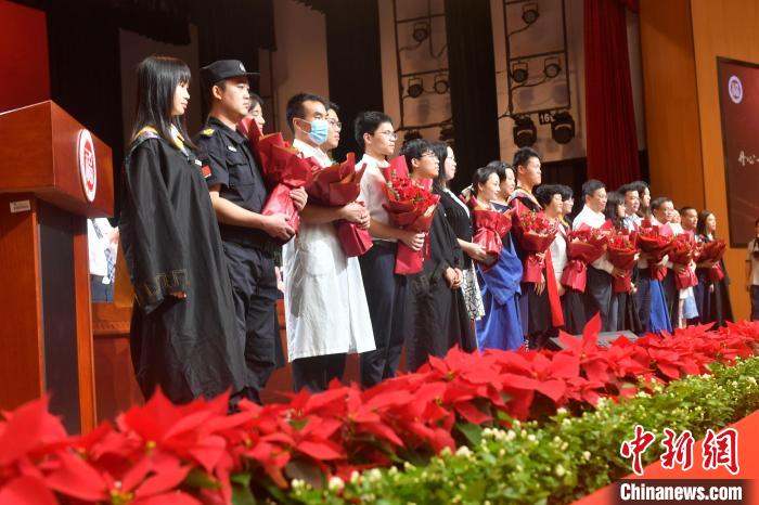 图为毕业生代表向教职员工代表献花。　吕明 摄