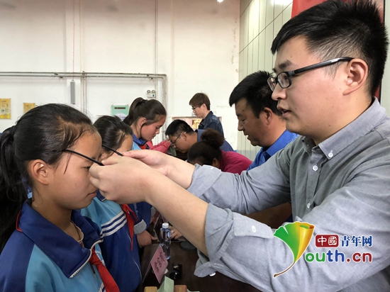 福州大学第十九届研究生支教团队长陈宪三营中学学生发放爱心眼镜。福州大学研支团 供图