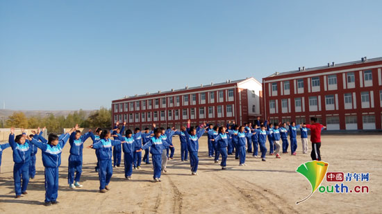 三营中学举行广播体操及队列队形比赛。图为福州大学支教团成员教学生做广播体操。